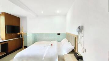Quarto de hotel com cama, televisão, escrivaninha e telefone.