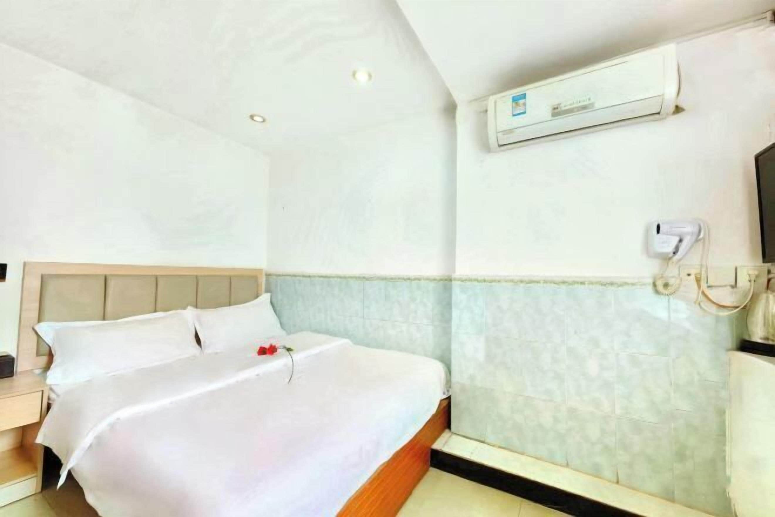Quarto de hotel com cama, mesa de cabeceira, ar-condicionado fixado na parede e banheiro com porta-toalhas.