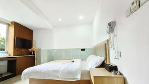 Une chambre d’hôtel moderne équipée d’un lit, d’une table de chevet et d’un téléviseur fixé au mur.