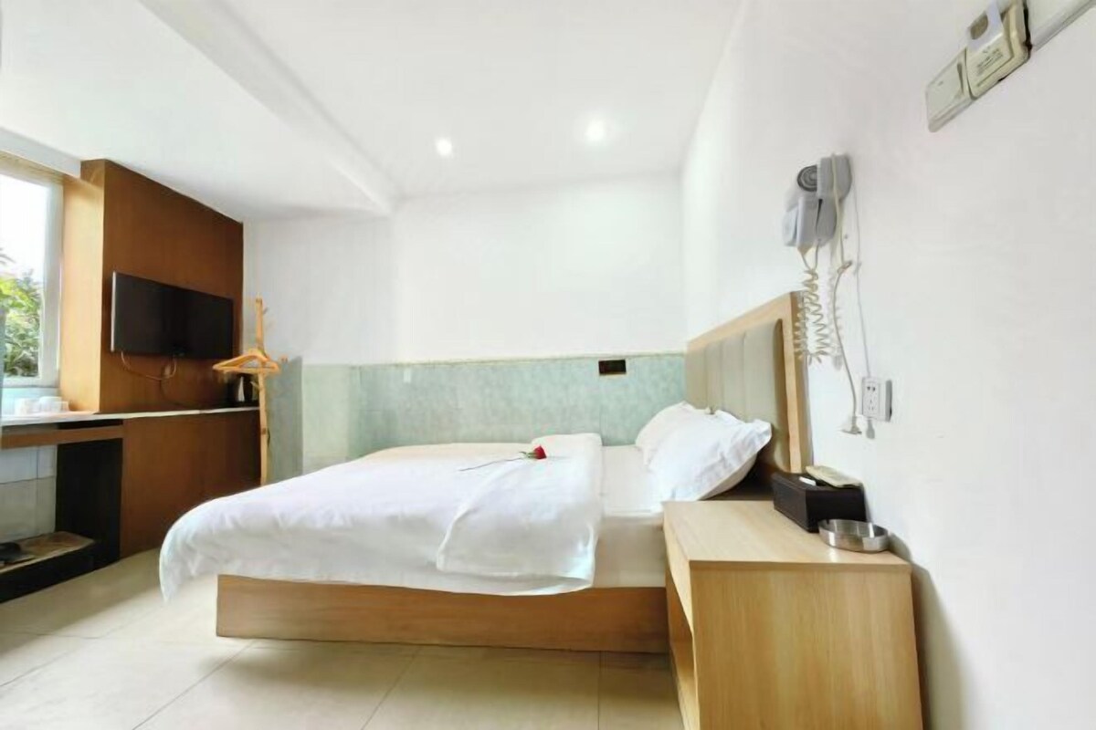 A modern hotel room with a bed, bedside table, and a TV mounted on the wall.