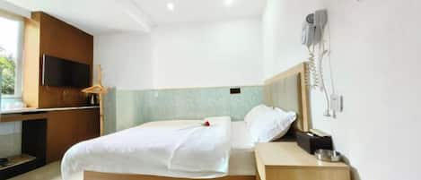 A modern hotel room with a bed, bedside table, and a TV mounted on the wall.