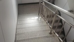 Een trap met metalen leuning en balustrade, die naar een verdieping leidt.