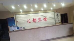 A reception desk with a glass partition and a sign in red characters.