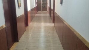 A corridor with a wooden floor and walls, leading to a door at the end.