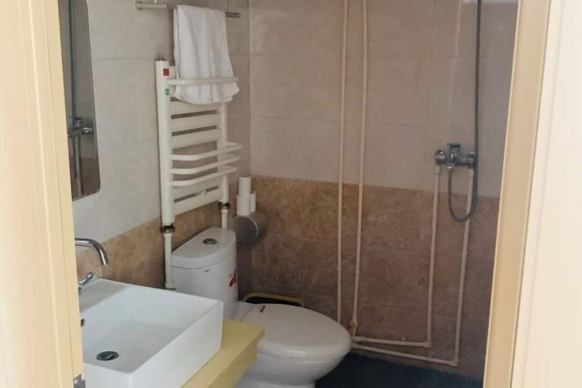 A small bathroom with a toilet, sink, and shower.