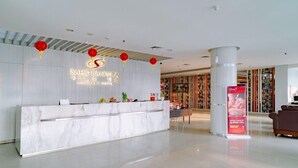 Un espace d’accueil moderne avec un comptoir en marbre, des lanternes rouges et une grande colonne.