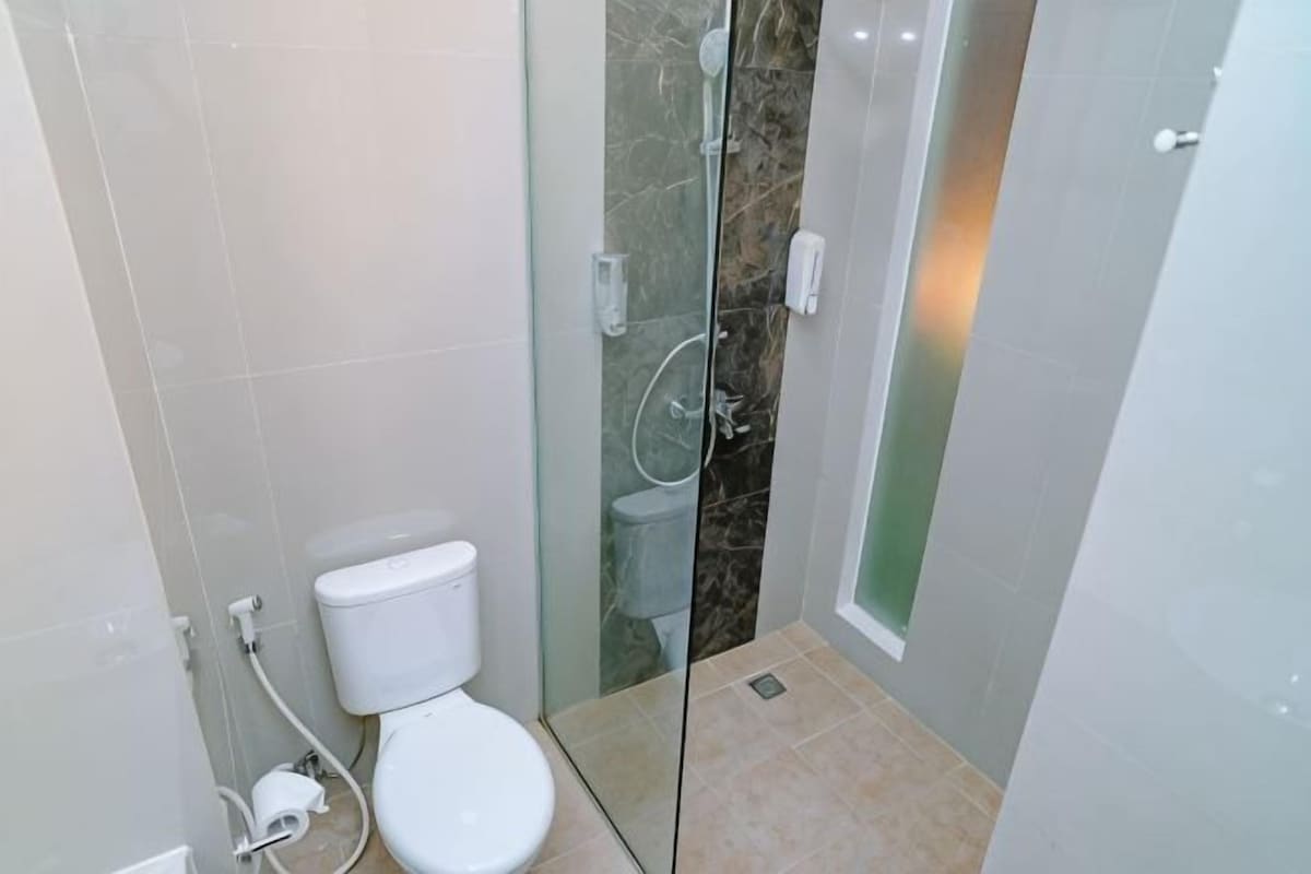 A bathroom with a glass-enclosed shower, a toilet, and a sink.