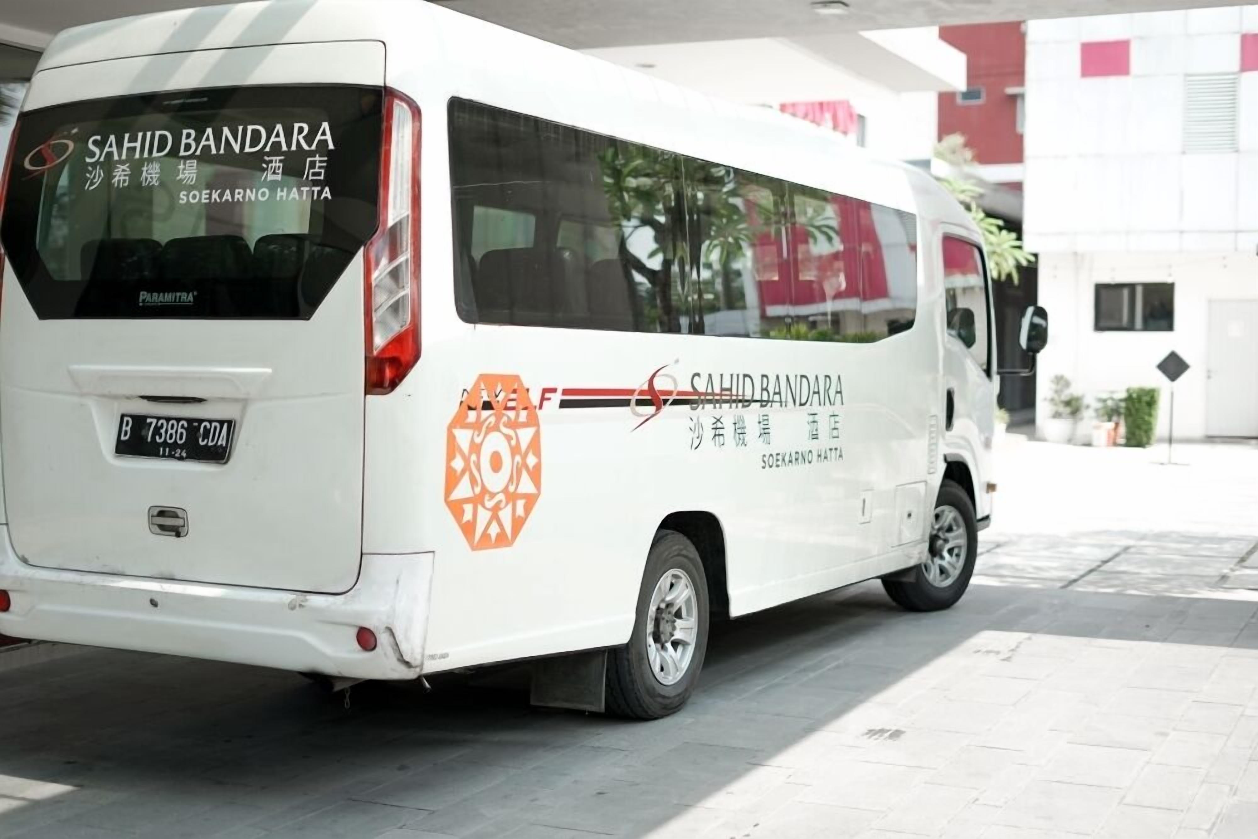 A white van with 'SAHID BANDARA' and 'SOEKARNO HATTA' branding, parked outside a building.