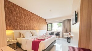 Une chambre d’hôtel avec un grand lit, des tables de chevet, un bureau et une télévision.