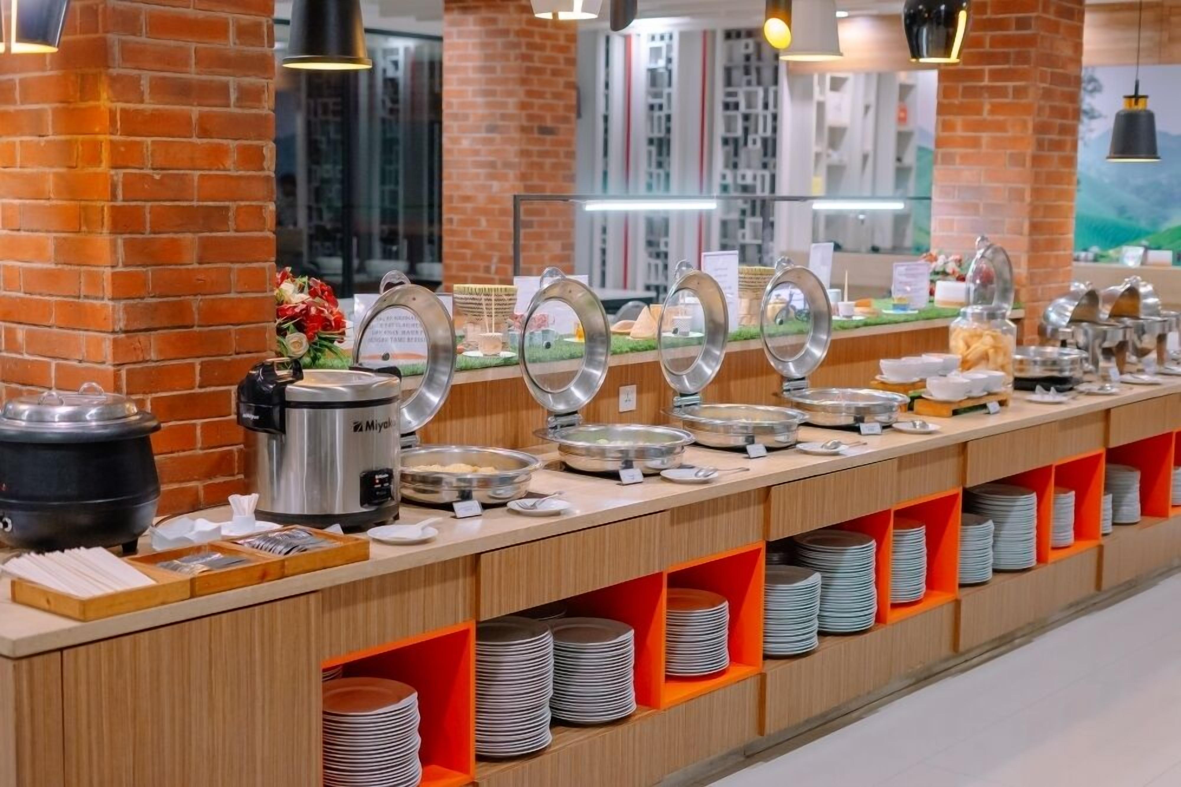 Un buffet avec différents récipients et ustensiles pour servir la nourriture, une machine à café et un mur en briques en arrière-plan.