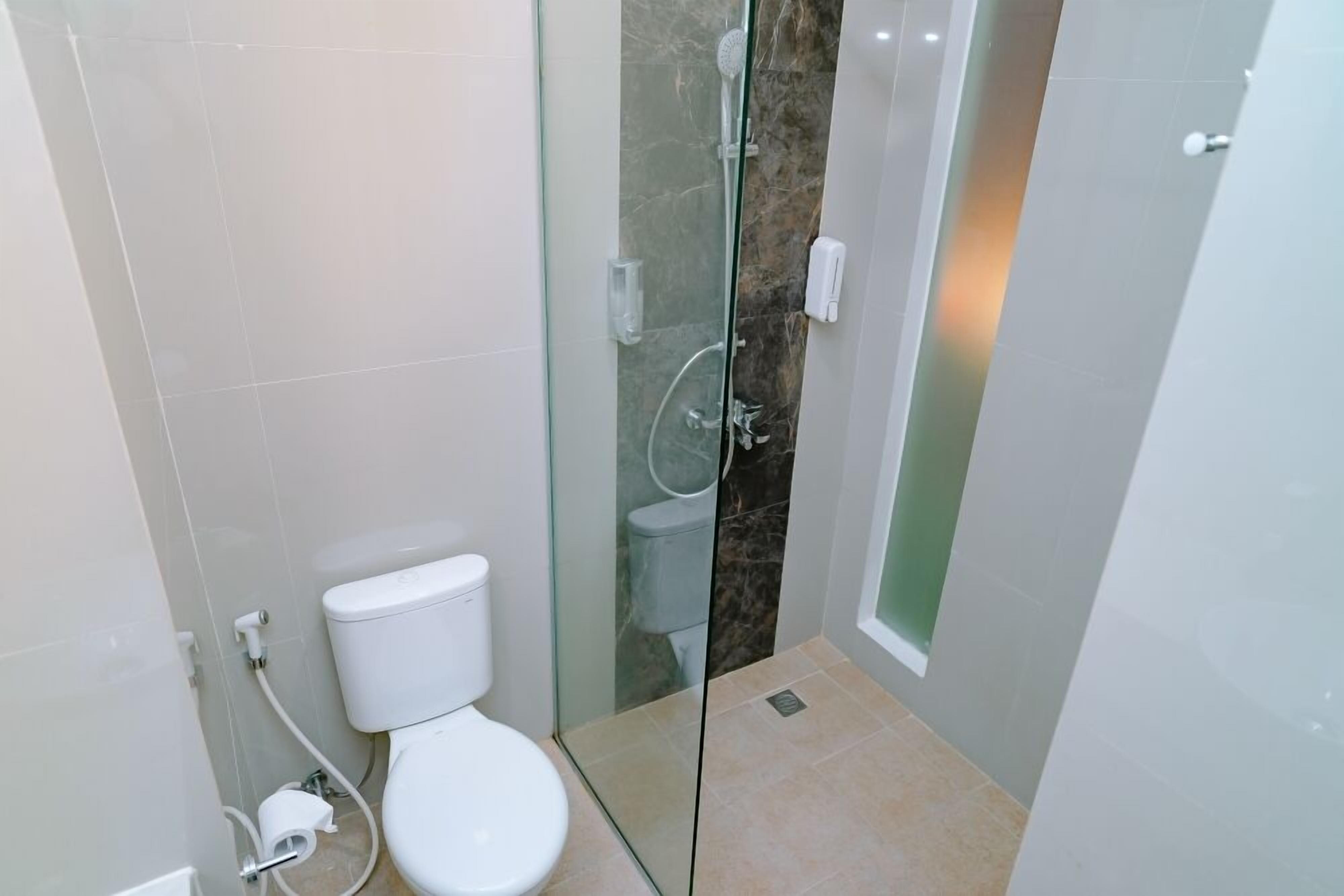 Une salle de bain moderne dotée d’une douche à parois de verre, de toilettes et d’un lavabo.