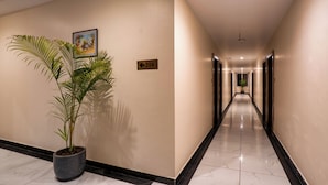 A hotel hallway with a potted plant, a directional sign, and a door marked with the number 214. - Hotel Aranyasutra (Udaipur)