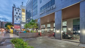 The Omni Tower hotel with a modern facade, a parking area, and a well-lit entrance. - Neom Town Residence (Bangkok)