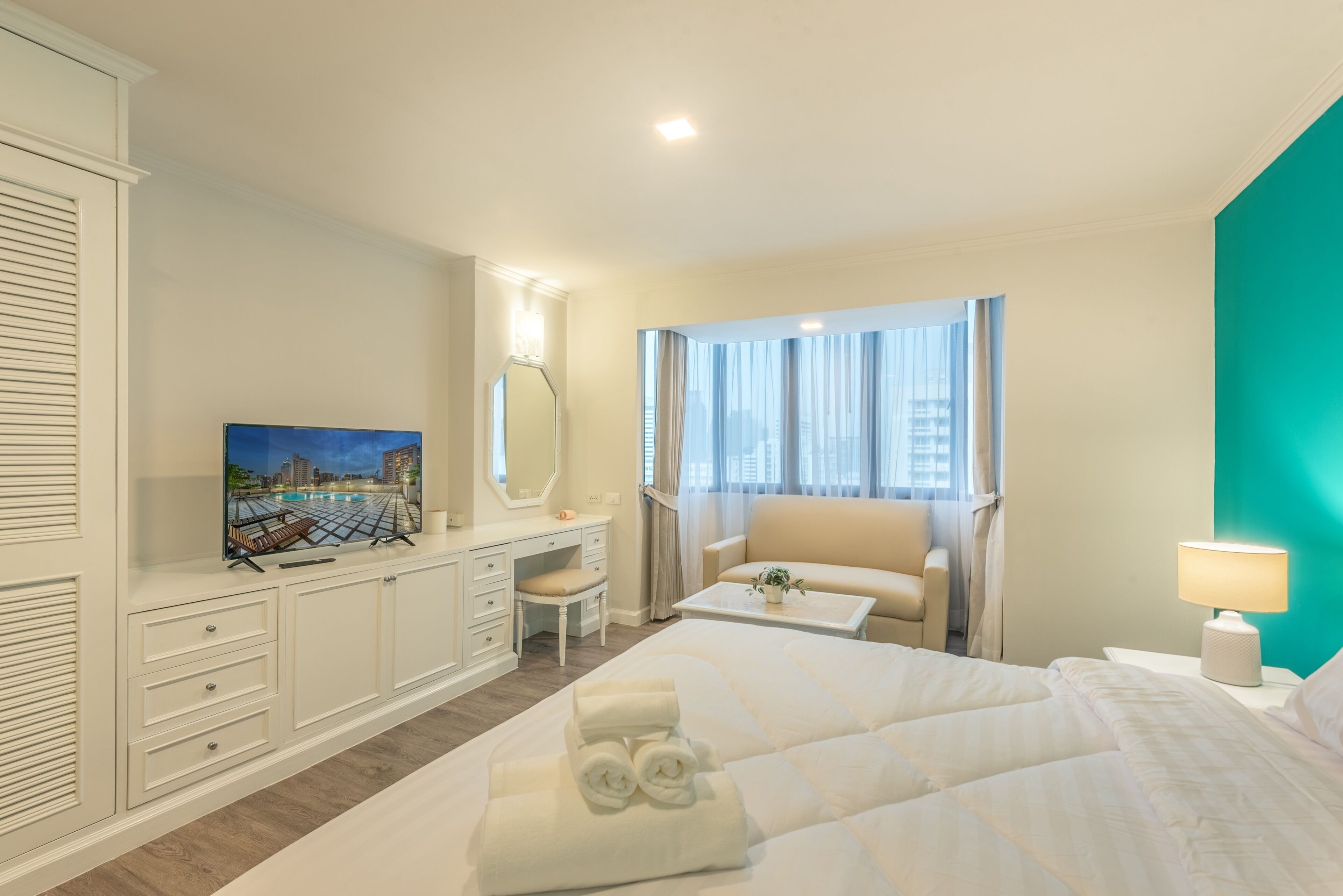 Een hotelkamer met een bed, een bureau met stoel, een televisie en een raam met gordijnen.