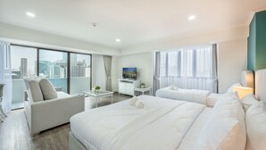 A modern hotel room with a large bed, a sofa, a desk, and a TV. - Neom Town Residence (Bangkok)
