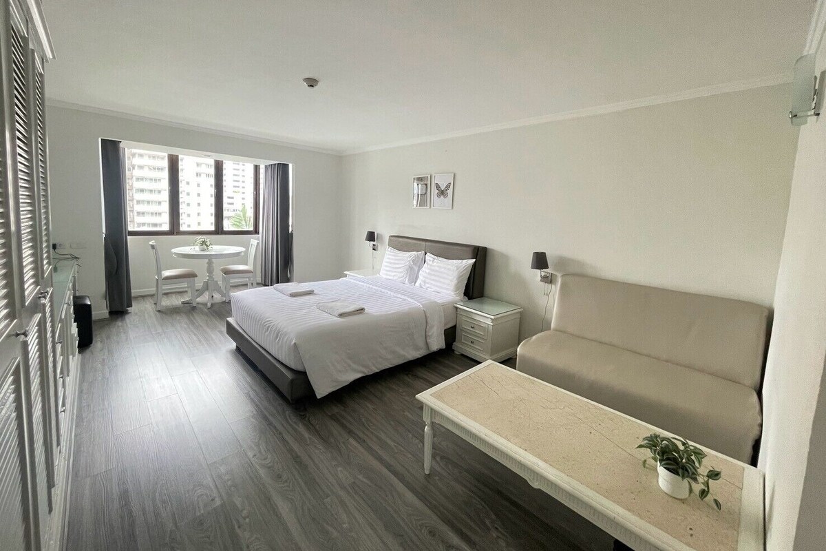 A hotel room with a bed, a sofa, a small table, and a window with curtains.