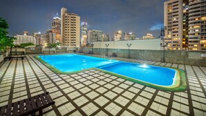 A rooftop swimming pool with two pools, surrounded by a tiled deck and lounge chairs. - Neom Town Residence (Bangkok)