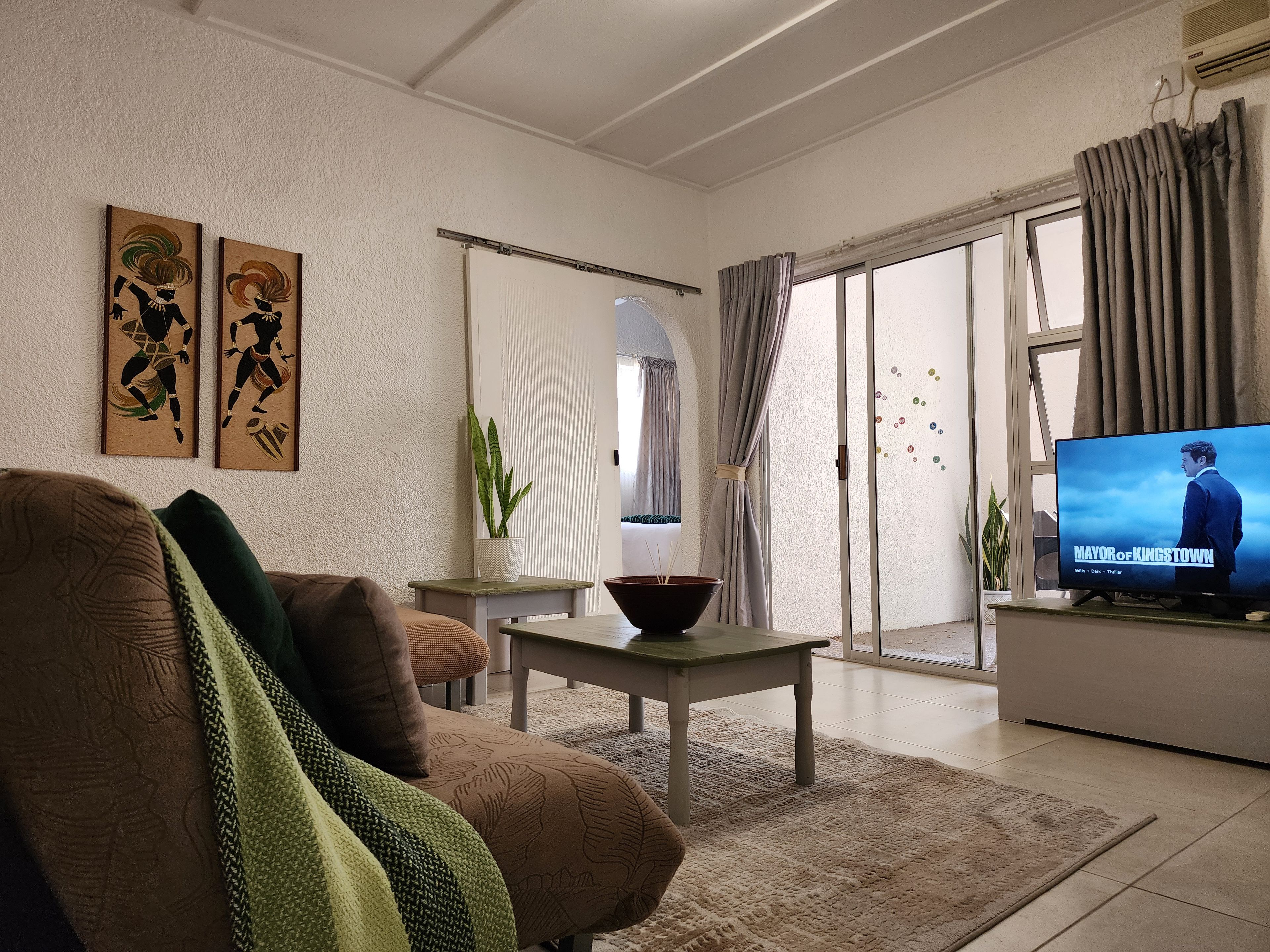 Una sala de estar con sofá, mesa de centro, televisor y puerta corrediza de vidrio que da a un balcón.
