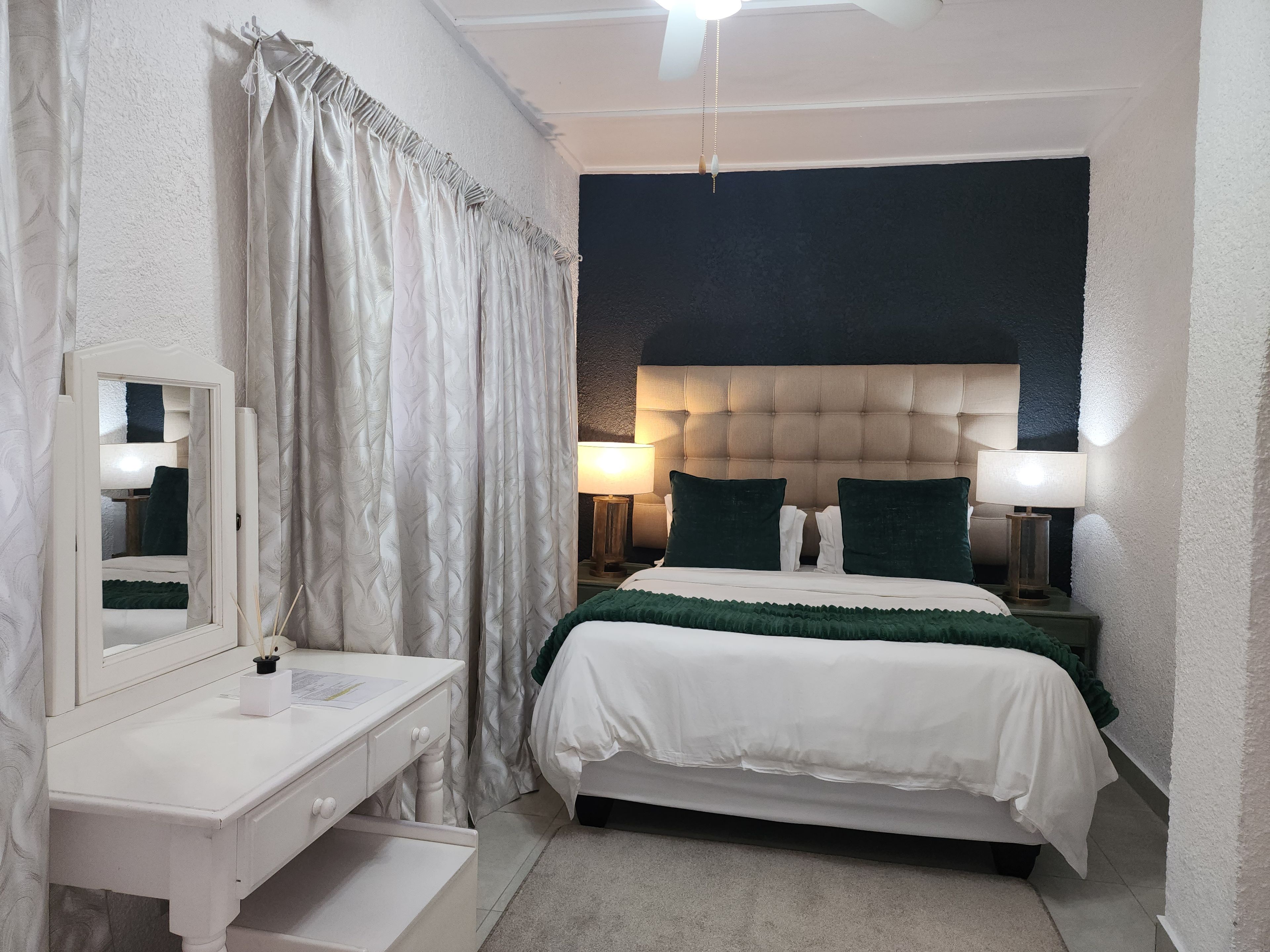 Un dormitorio con cama, lámparas de noche, un espejo y cómoda.