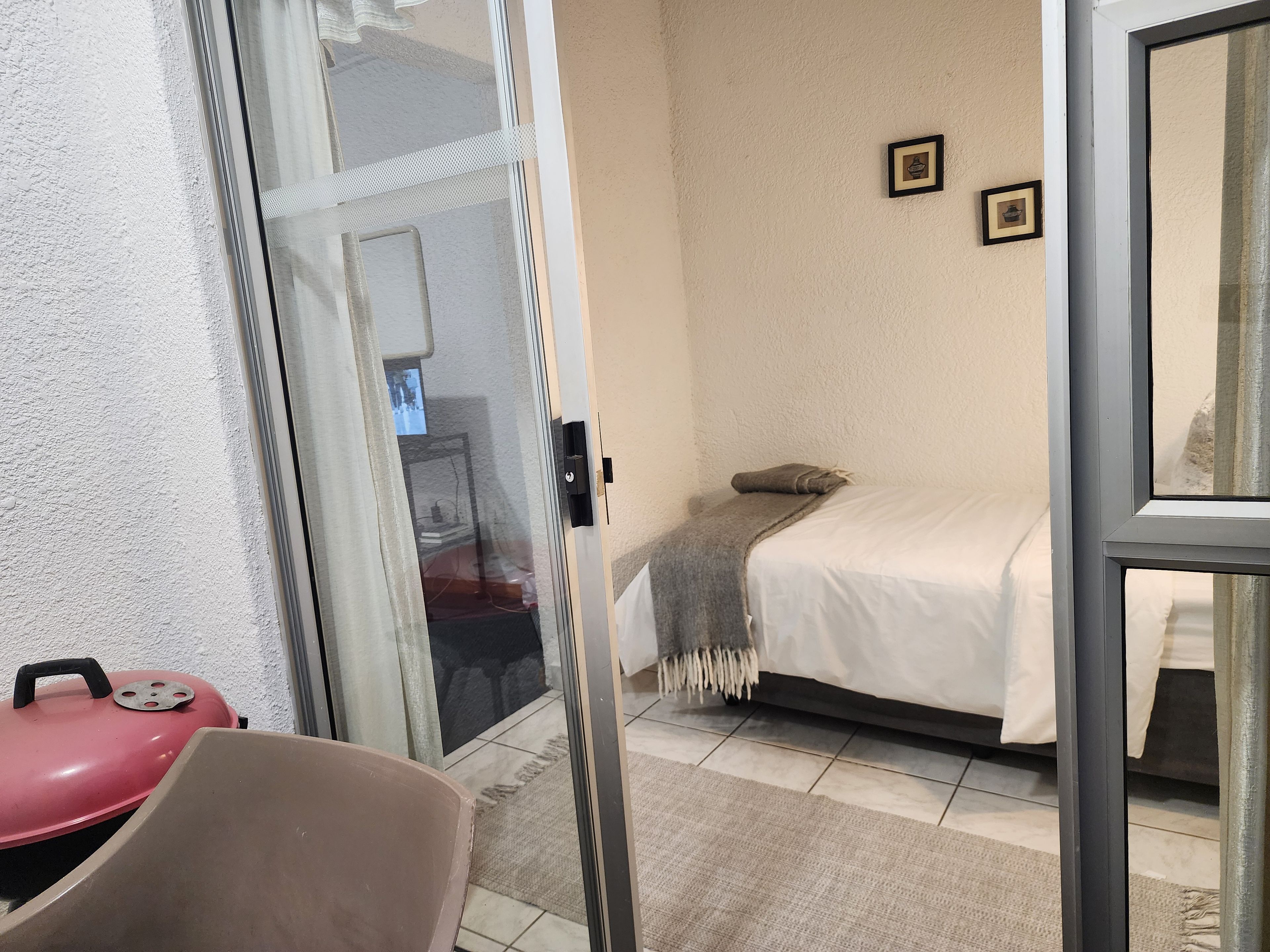 A room with a bed, a small table, a chair, and a sliding glass door leading to an outdoor area.