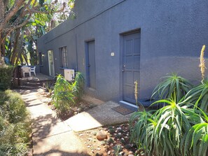 A building with a blue exterior, a door, and a small outdoor seating area with a table and chairs. - Room-busa House Self Catering Guest Hous (Mbombela)