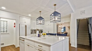 A spacious kitchen with a large island, white cabinetry, and modern pendant lighting. - Buckhead 4-BDM/3.5 Bath, chic house, w baby grand Piano. Mins to Shopping/Gov Mn (Atlanta)