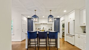 A kitchen with a central island, bar stools, pendant lights, and white cabinetry. - Buckhead 4-BDM/3.5 Bath, chic house, w baby grand Piano. Mins to Shopping/Gov Mn (Atlanta)