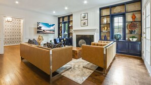 A spacious living room with a fireplace, leather sofas, and a large window with a view. - Buckhead 4-BDM/3.5 Bath, chic house, w baby grand Piano. Mins to Shopping/Gov Mn (Atlanta)