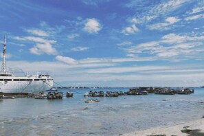 A large ship docked at a pier with calm water and a clear sky. - JUNTING HOTEL (Zhanjiang)