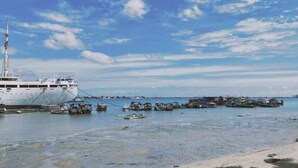 Un gran barco atracado en un puerto con varias embarcaciones más pequeñas cerca.