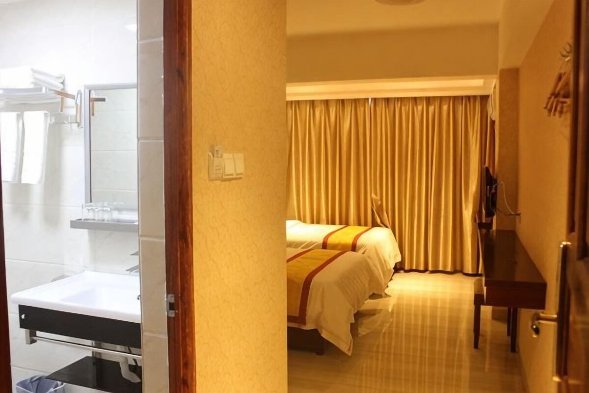 A hotel room with a bed, a bedside table, a mirror, a window with curtains, and a door.