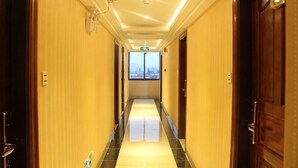 Pasillo de hotel con puertas a ambos lados, suelo de baldosas y vista al final del corredor.