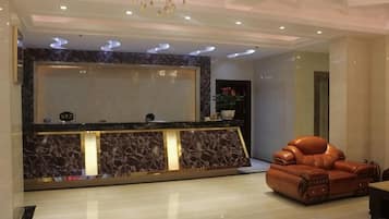 A reception area with a marble counter, a leather sofa, and a chandelier.