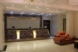 A reception area with a marble counter, a leather sofa, and a chandelier. - JUNTING HOTEL (Zhanjiang)