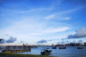 Une promenade au bord de l’eau, avec des bateaux et, au loin, la silhouette d’une ville.