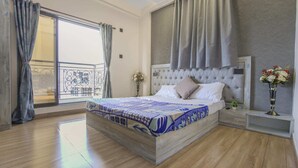 A bedroom with a large bed, a balcony, and a view of the city. - 3BHK w/Pool - Sunset Palazzo by Universe Villas (Karjat)