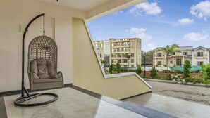 A room with a hanging chair, a view of residential buildings, and a tiled floor. - 3BHK w/Pool - Sunset Palazzo by Universe Villas (Karjat)