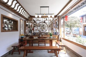 Un espace repas avec une table en bois, des bancs et un lustre.