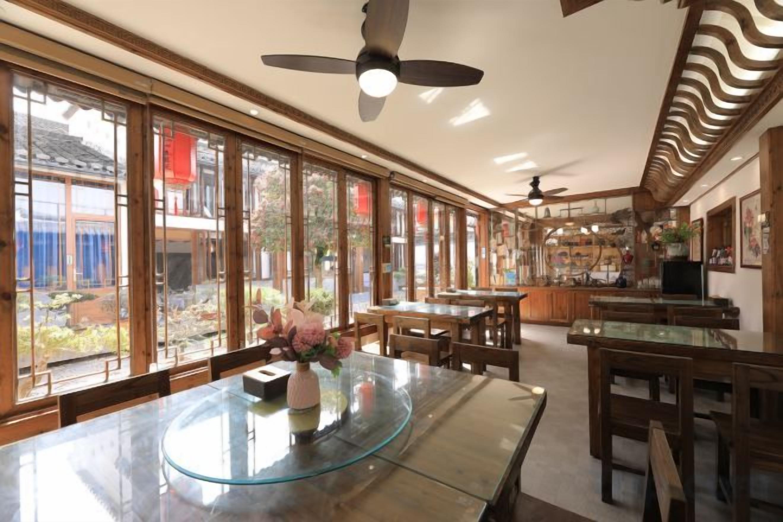 A spacious room with a large dining table, multiple chairs, and a ceiling fan.