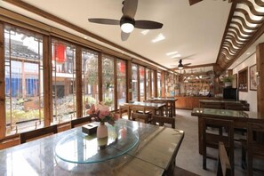 Une pièce spacieuse avec une grande table à manger, plusieurs chaises et un ventilateur de plafond.