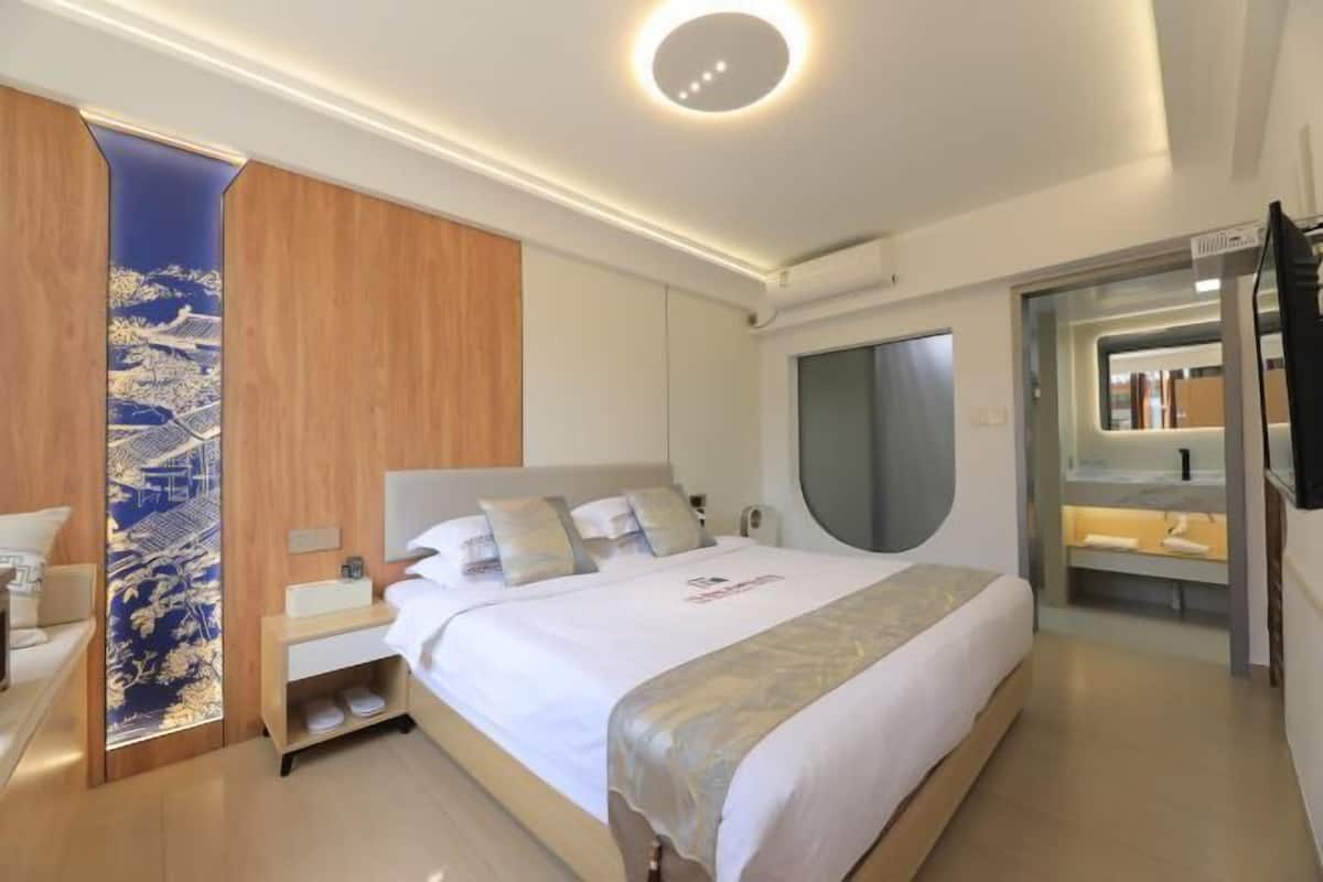 Una habitación de hotel moderna con una cama grande, un armario empotrado, un tocador con espejo y un diseño de pared único.