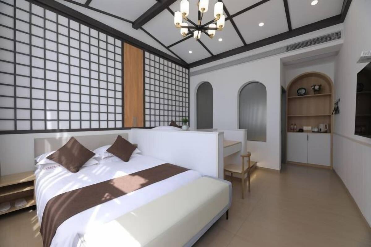 Una habitación de hotel moderna con una cama grande, un escritorio y una kitchenette.