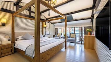 Une chambre à coucher avec un lit à baldaquin, une tête de lit en bois, des tables de chevet, un bureau et une grande fenêtre.