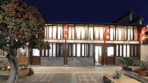 A traditional building with large windows and a tiled courtyard.