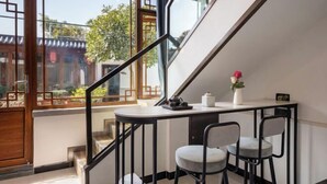 A staircase with a railing, a small table with chairs, and a view of traditional architecture outside.