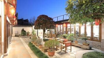 A courtyard with potted plants, a wooden bench, and a pathway.