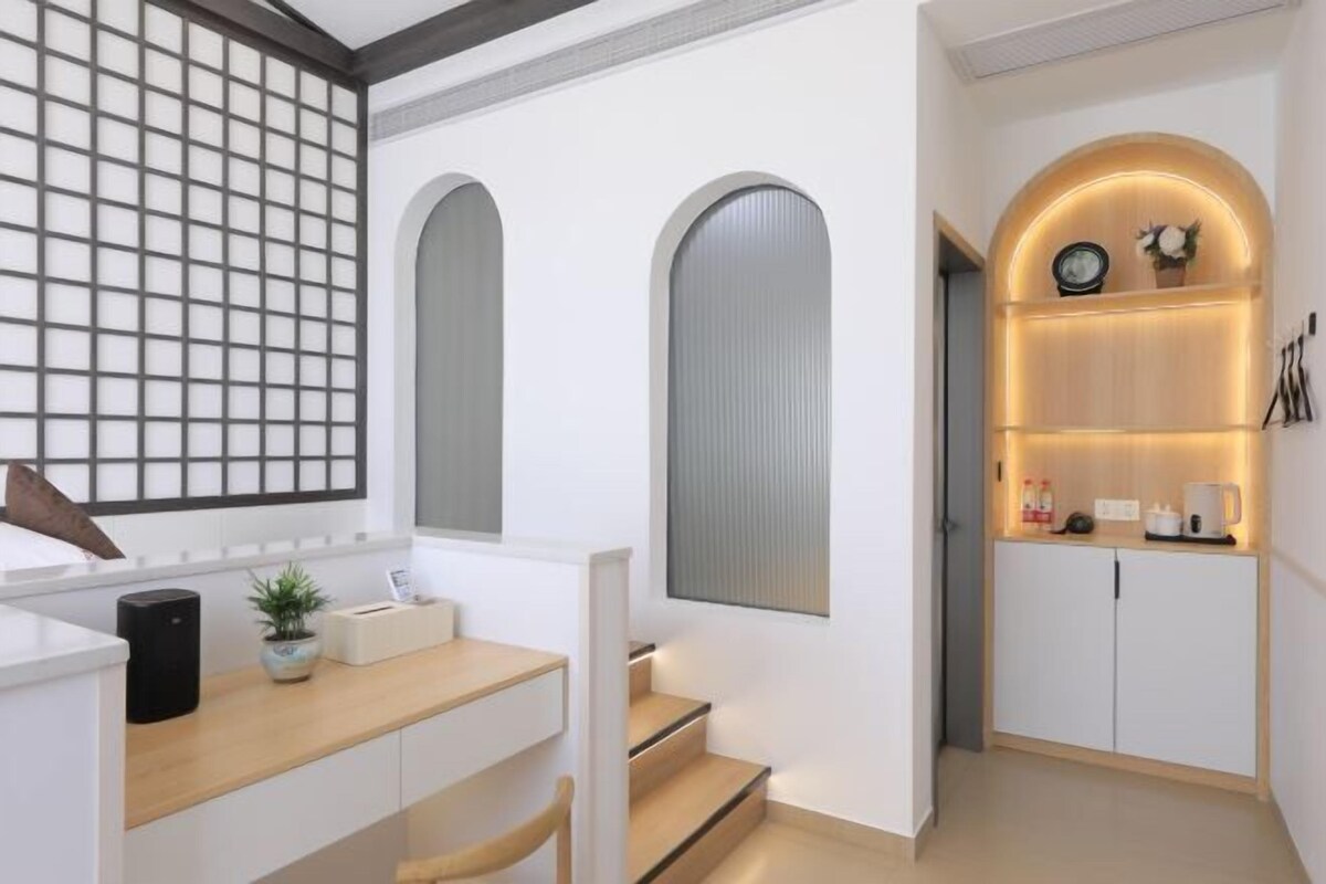 Una cocina moderna con armarios blancos, encimera de madera y horno empotrado. Hay una planta pequeña en la encimera y una cafetera en el estante.