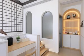 Una cocina moderna con armarios blancos, encimera de madera y horno empotrado. Hay una planta pequeña en la encimera y una cafetera en el estante.