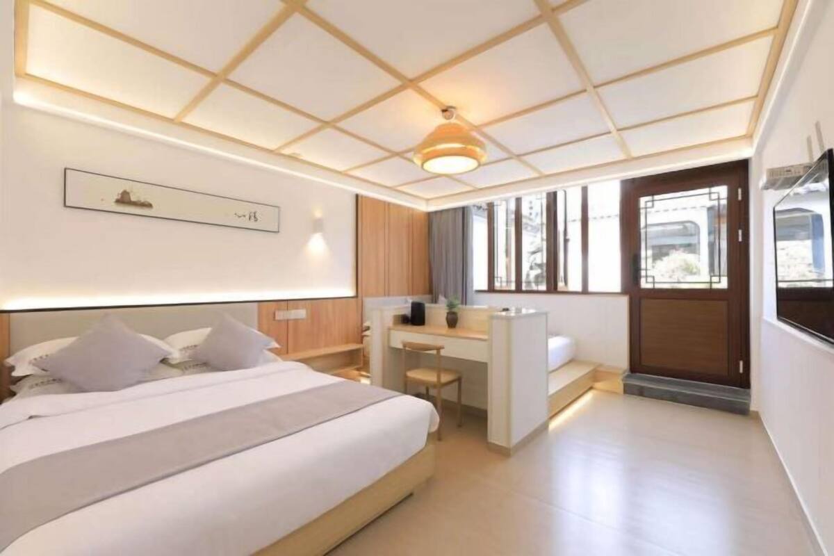 Una habitación de hotel moderna con una cama grande, un escritorio y vistas al exterior.