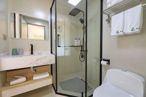 Un baño moderno con ducha de vidrio, inodoro blanco, encimera de mármol y toallero con toallas.
